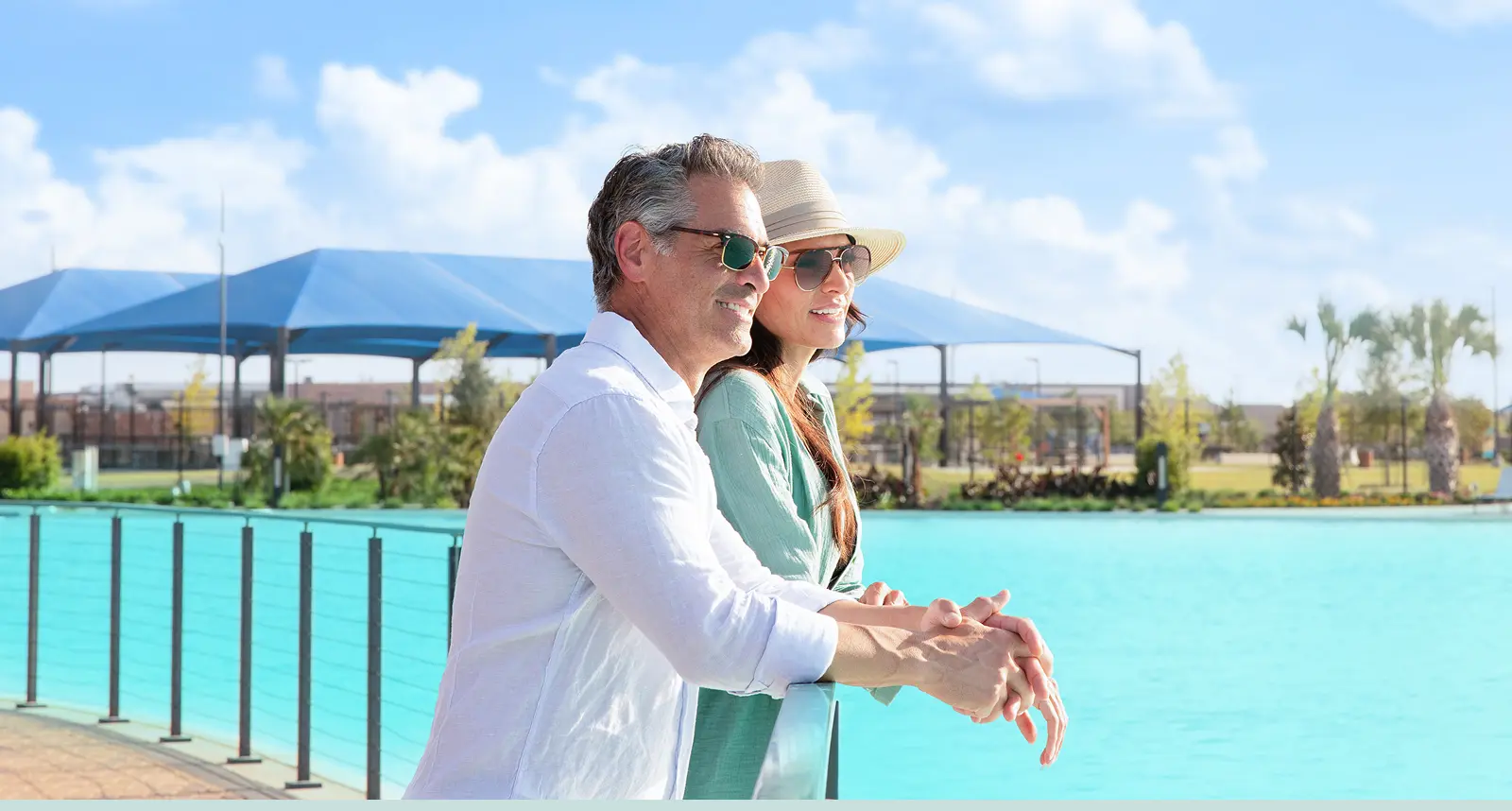 A man and woman enjoy the waterfront view near new homes on a sunny day.