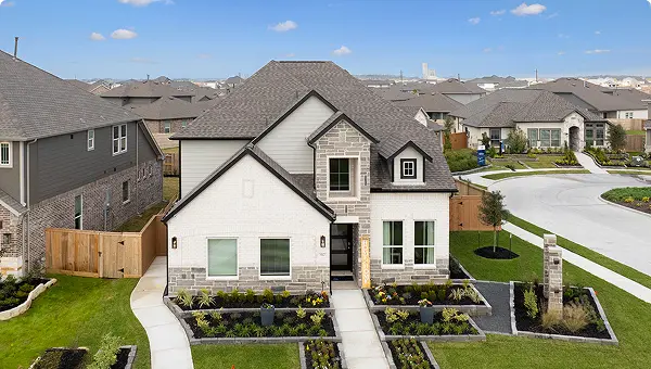 Two-story suburban house in Magnolia TX with a front lawn and landscaped garden on a sunny day.